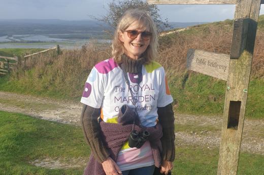 Supporter wearing a Royal Marsden Cancer Charity t-shirt standing by South Downs signpost