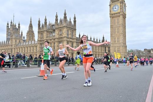 A Team Marsden runner wearing a charity running top smiles at the camera in front of Big Ben during the London Landmarks Half Marathon 2023