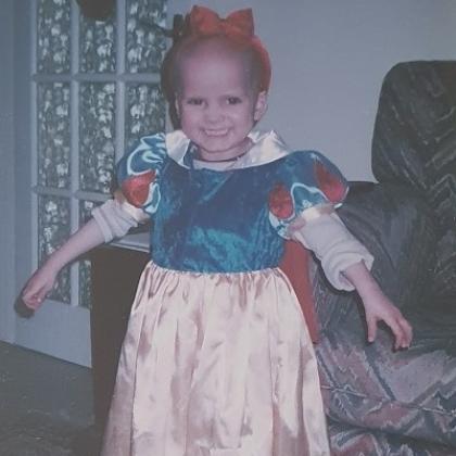 A young child smiling in a Snow White dress