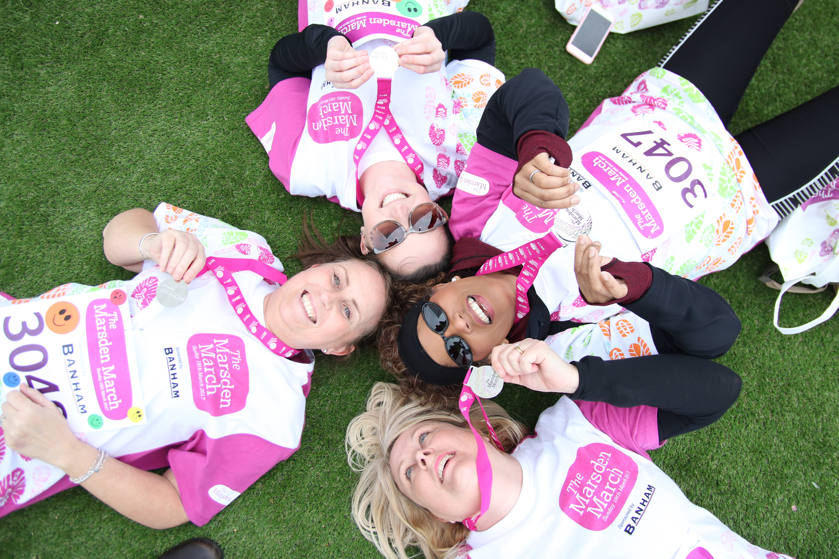 Marsden Marchers lie down on the grass with medals