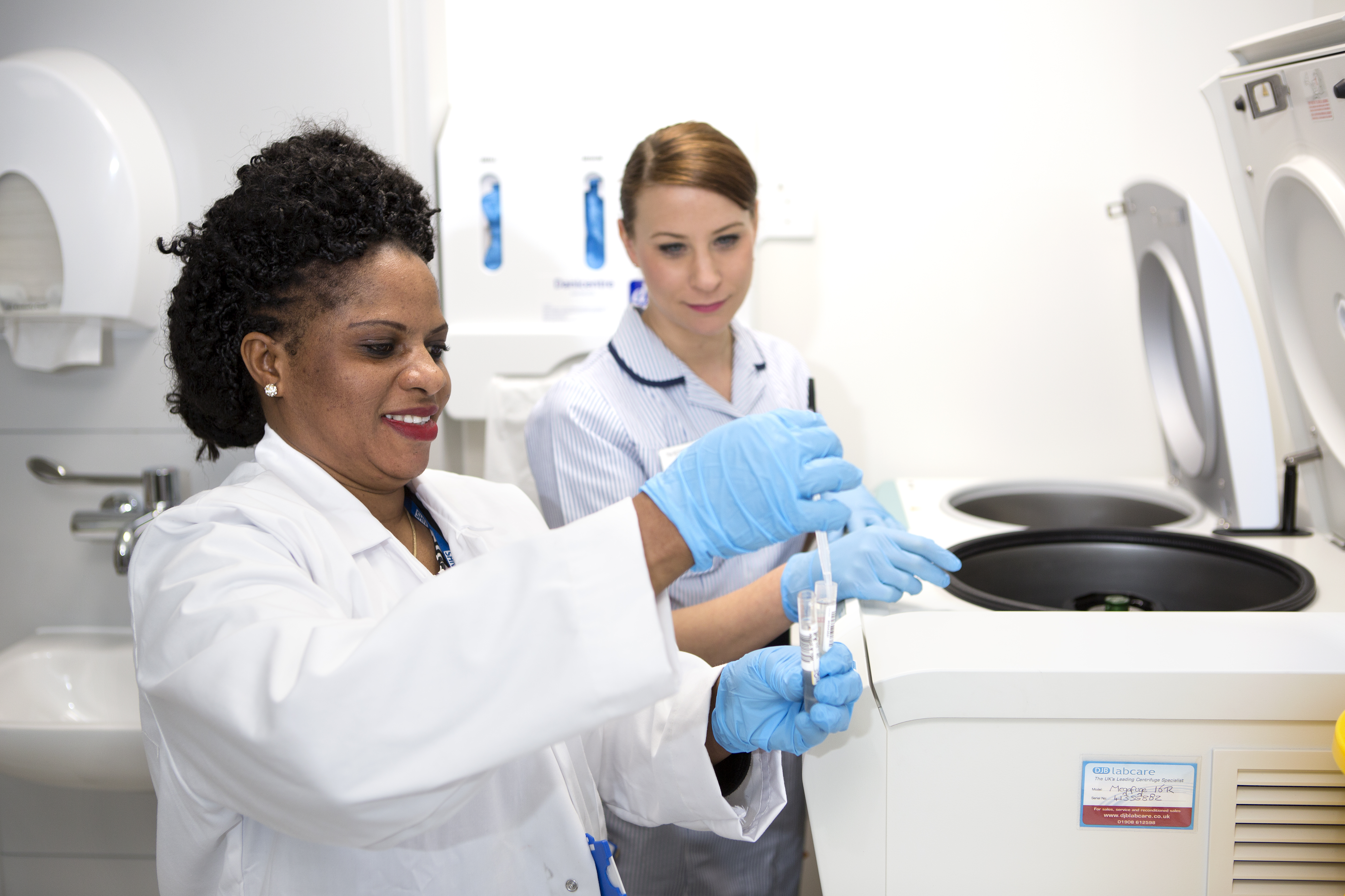 Two medical research staff at The Royal Marsden prepare a sample for a centrifuge. 