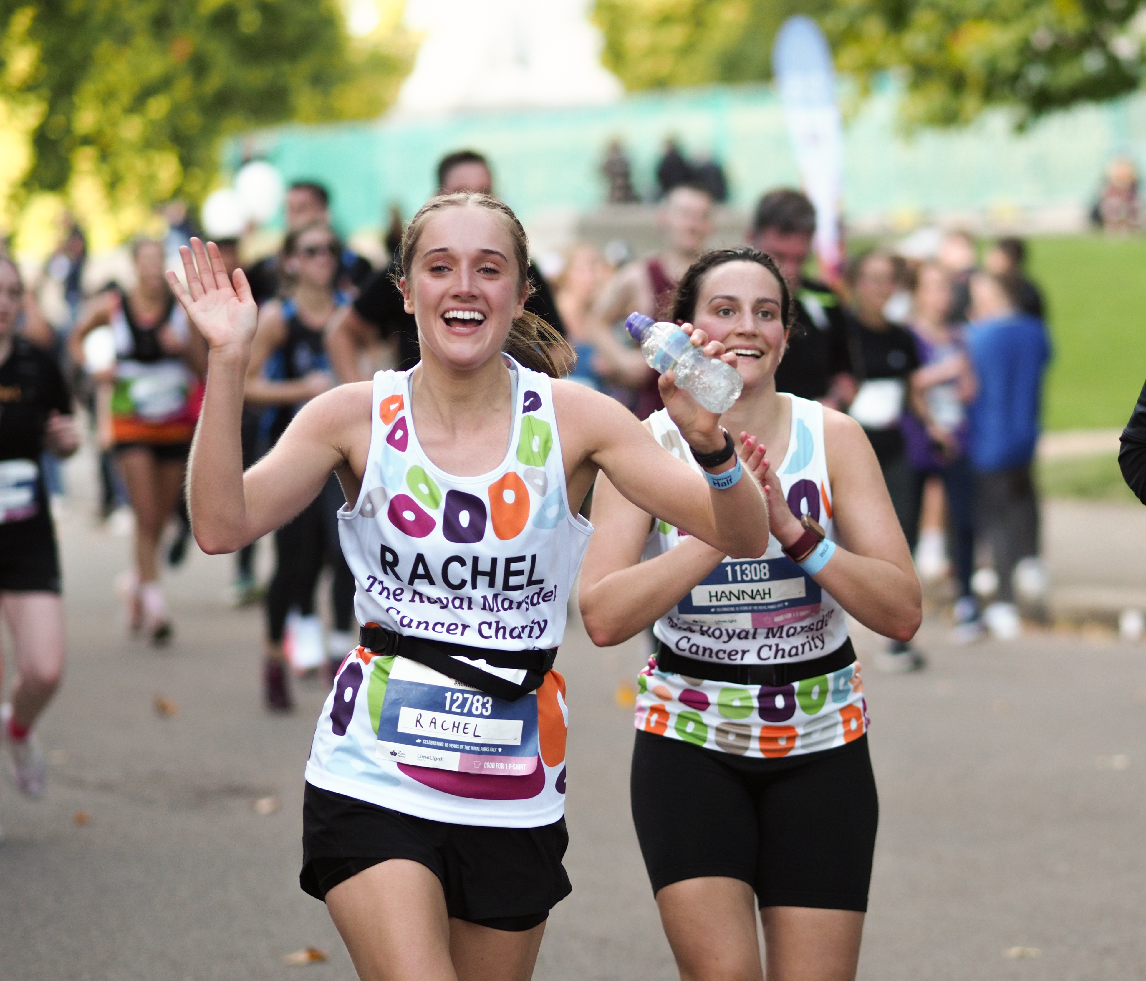 Two Team Marsden runners taking part in the Royal Parks Half Marathon 2022, waving at the camera.