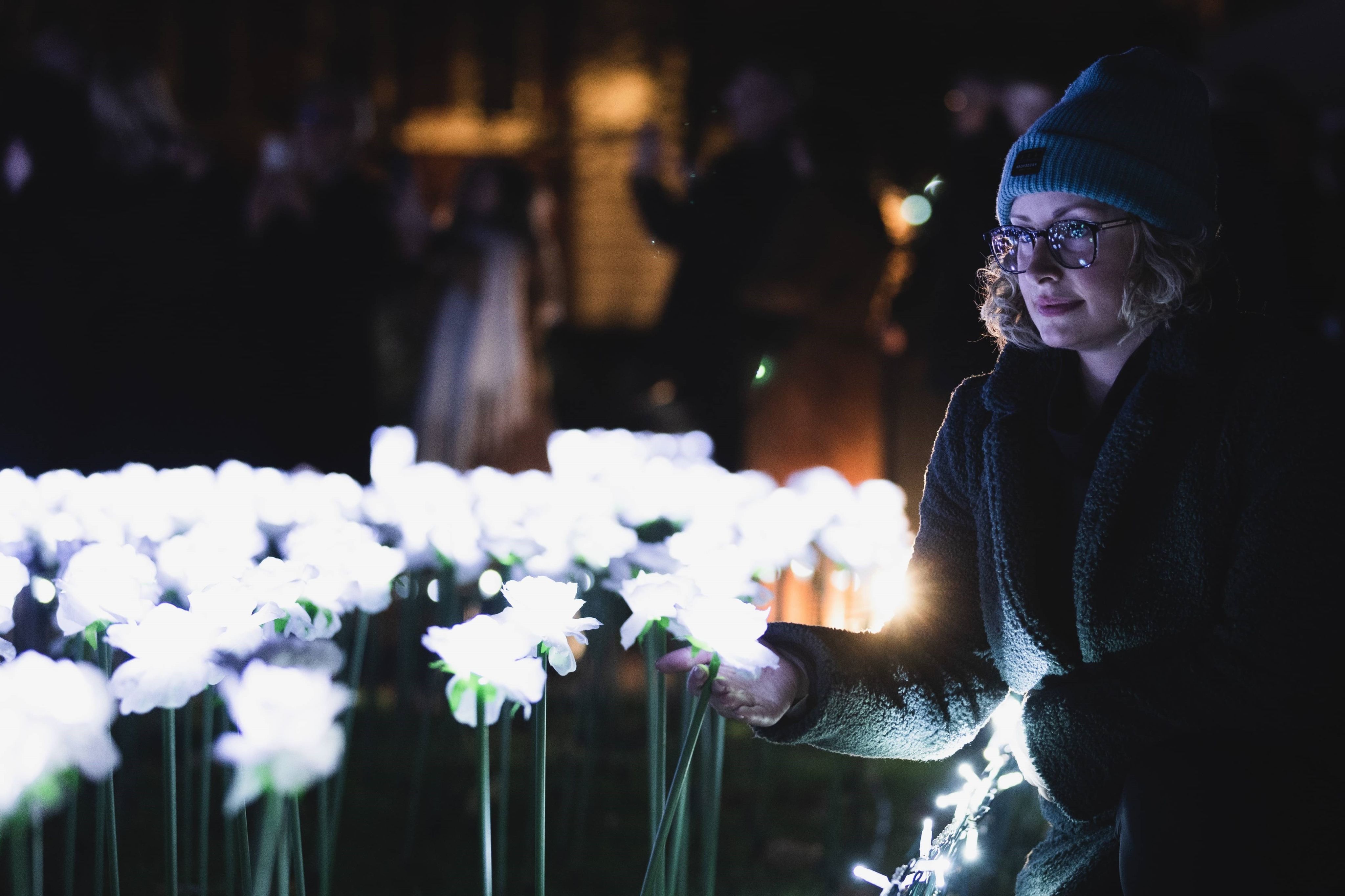 A young woman looking at the glowing roses. She looks reflective and peaceful.