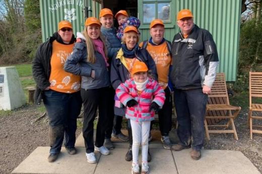 Christine and Family outdoors wearing their orange Marsden March shirts and caps