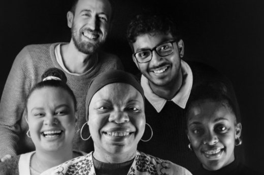 Black and white photo of Debbie (front and centre) smiling surrounded by 4 other family members