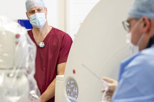 HRH Duke of Cambridge in surgical scrubs, watching a consultant (male) perform a procedure on a patient