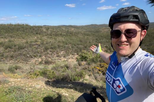 Chris wearing his cycle shirt and helmet in a rural spanish landscape