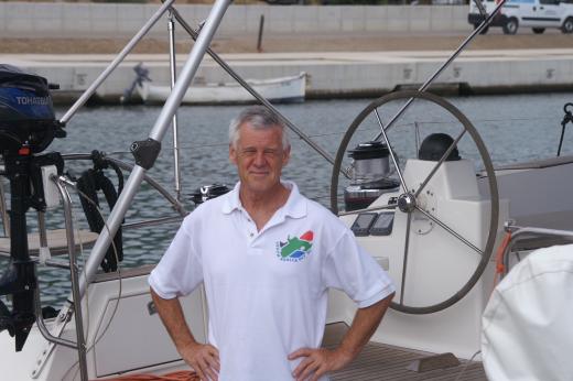 Michael Thick standing on a boat. his hands are on his hips and he is wearing a white polo shirt.