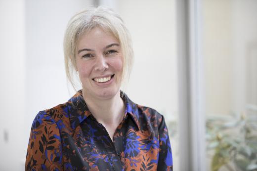 Dr Anna Minchom smiling. She has blonde hair and is wearing a red and blue patterned shirt