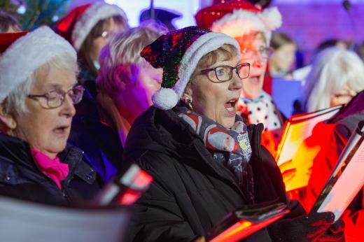 colourful photo of carol singers wearing Santa hats at a Celebrate A Life service