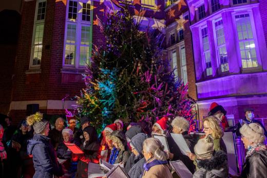 Carol singers standing in front of the lit up Christmas tree in outside The Royal Marsden hospital in Chelsea London