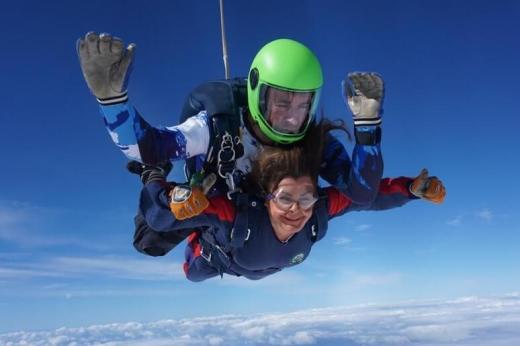 Louise skydiving. She is wearing goggles and smiling. 