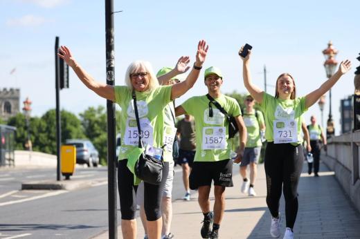 A group of three taking part in the Banham Marsden march. They are smiling and have their hands in the air