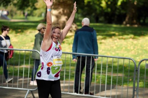 A Team Marsden runner waves her hands in the air as she passes the camera during the Royal Parks Half Marathon