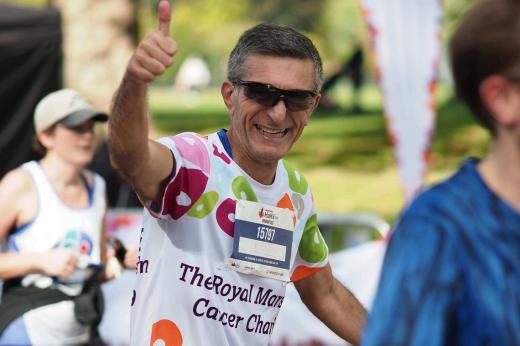 A Team Marsden runner wearing a charity running top smiles at the camera and gives a thumbs up during the Royal Parks Half Marathon 2022