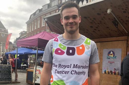 George in a Royal Marsden Cancer Charity running vest, standing in a busy town market