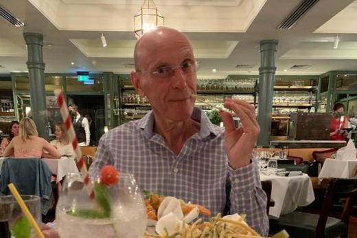 A man at a dinner table in a restaurant playing with chop sticks