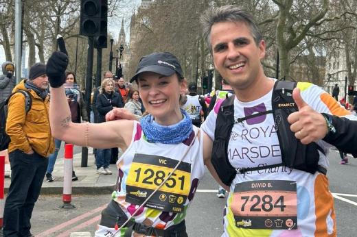 Two people in running gear smiling and giving a thumbs up