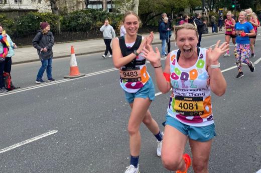 Two people smiling and laughing while running along a closed road in London