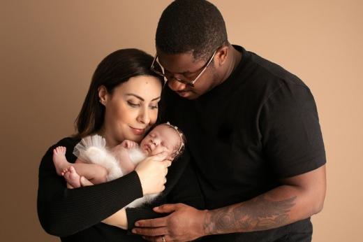 Two people looking down and smiling at a newborn baby