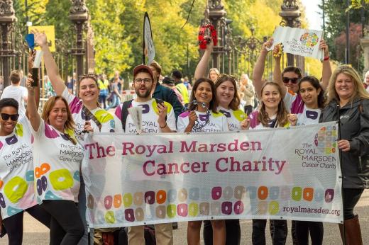 A group of people holding a Royal Marsden Cancer Charity banner and standing outside a park gate