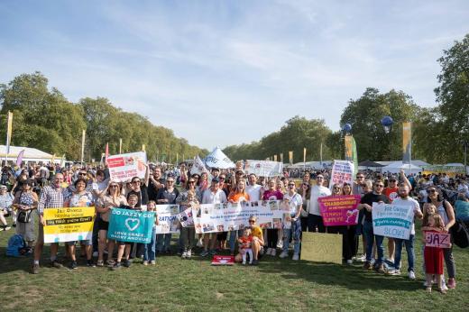 A large group of around 20 people holding up support signs and banners