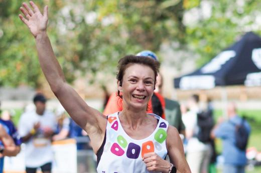 A Royal Parks Half Marathon runner smiling and waving at supporters