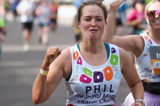 A Royal Parks Half Marathon Runner for The Royal Marsden Cancer Charity, fist-pumping as she runs past supporters