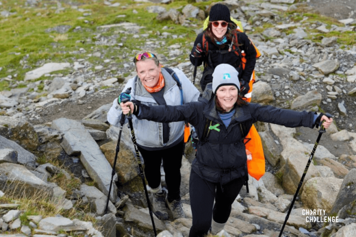Three trekkers smiling on a rocky hill face 