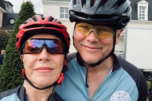 Two people wearing helmets, cycling sun glasses and Royal Marsden Cancer Charity cycling gear
