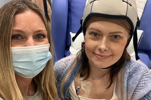 Aneta with a friend, wearing a chemotherapy cold cap with a port fitted on the righthand side of her chest