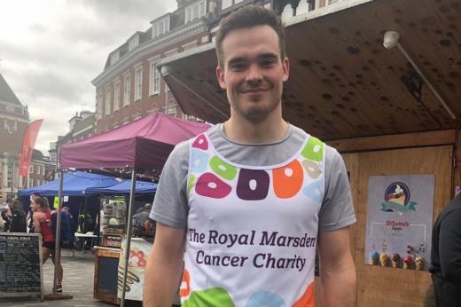 George in a Royal Marsden Cancer Charity running vest, standing in a busy town market