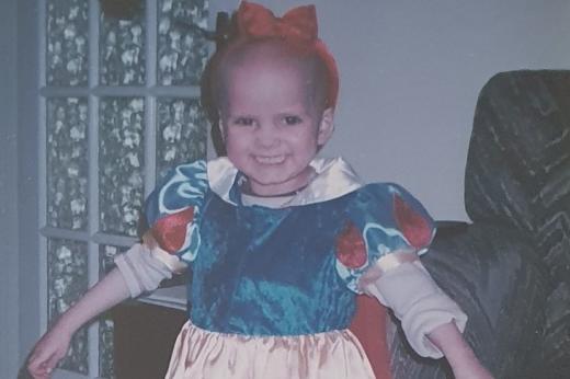 A young child smiling in a Snow White dress