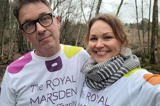 Two people in Royal Marsden Cancer Charity t-shirts smiling and walking in a wooded area
