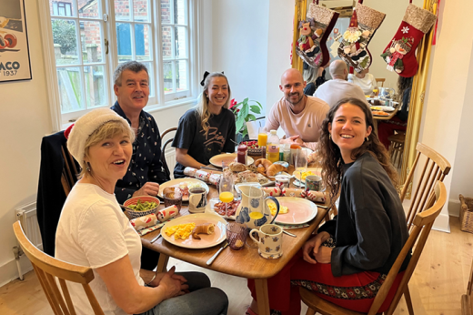 Five people sat around a dinner table, smiling