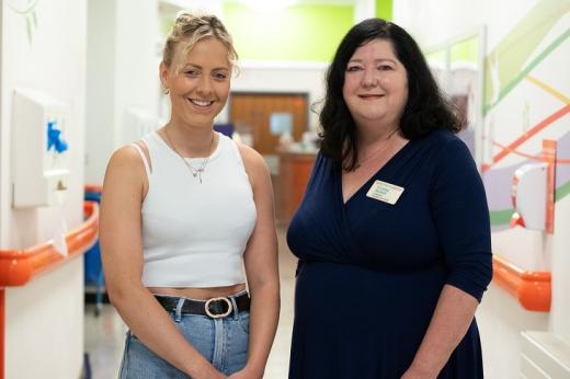 A Royal Marsden patient and a consultant smiling and standing in a corridor of a hospital