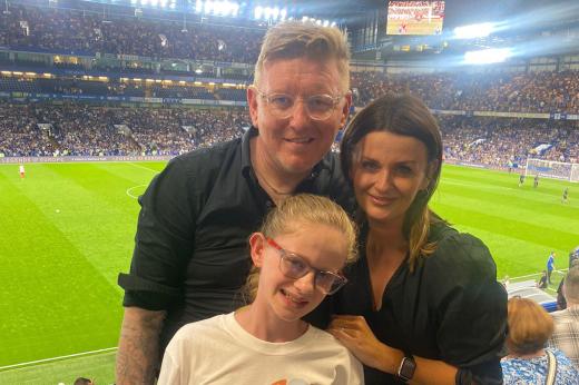 Morven MacDonald and her parents at Chelsea FC game, smiling at the camera.