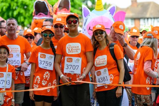 Several people wearing orange, standing in front of orange tape, smiling