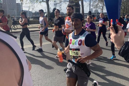 Runner smiles at camera as he passes with River Thames in the background 