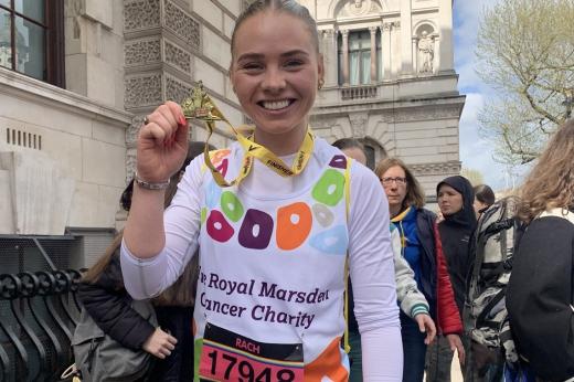Runner smiles and holds medal up 