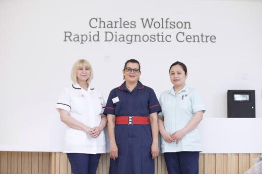 Three members of staff, two healthcare assitants and a matron, standing below the sign for the Charles Wolfson Rapid Diagnostic Centre