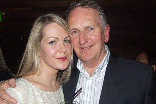 Royal Marsden patient Phillip wearing a suit and smart shirt. He has his arm around his daughter, who is a young woman with blonde hair, and wearing a white floral top. She is holding a drink