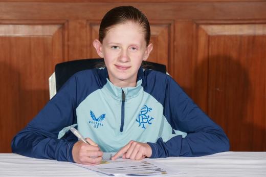 Morven, aged 11 signing with Glasgow Rangers. She is wearing blue sports kit and has her hair tied back.