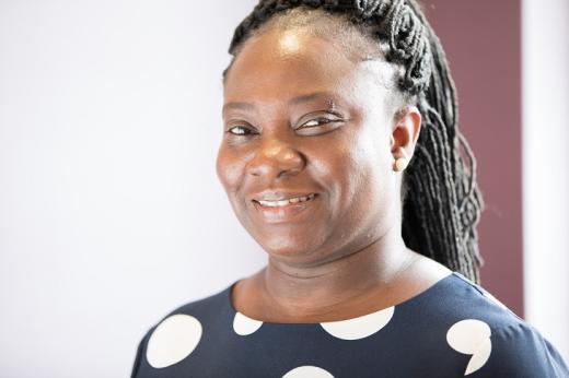 A headshot of The Royal Marsden's Sarah Adomah. She is smiling and wearing a smart navy top with big white polkadots.