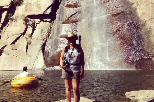Female trekker standing in front of river and rocks