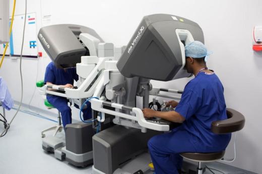 Two trainee surgeons sitting at two consoles, which is controlling a robot.