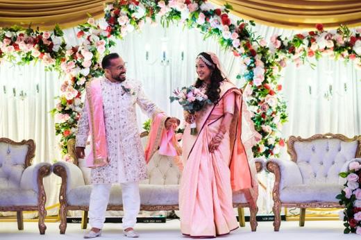 A man and a woman on their wedding day, dressed in brightly coloured clothes, smiling at each other