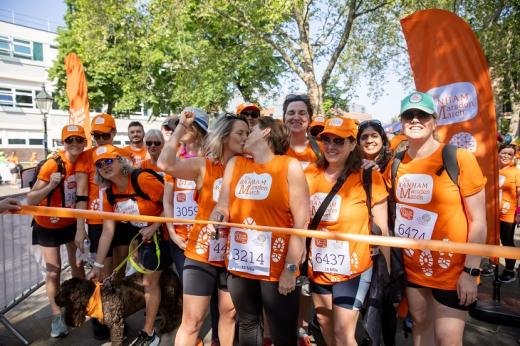 Sue and Alex kissing at the starting line of the Banham Marsden March. There is a crowd of people with orange Banham Marsden March t-shirts standing behind them
