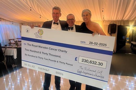 Three people dressed smartly at an event in a white marquee/ They are all holding up a giant cheque for £230,632.30 addressed to The Royal Marsden Cancer Charity.