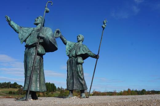 Two statues of people holding staffs and pointing to the skies along the Camino de Santiago trek